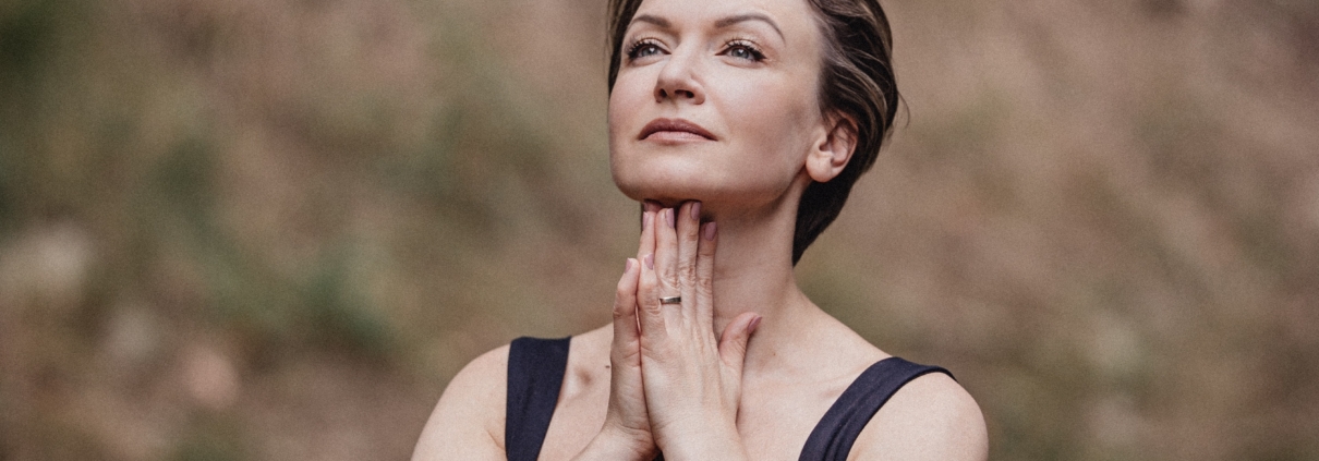 Maria Wade, executive coach and author, in a reflective pose outdoors with hands folded beneath her chin.