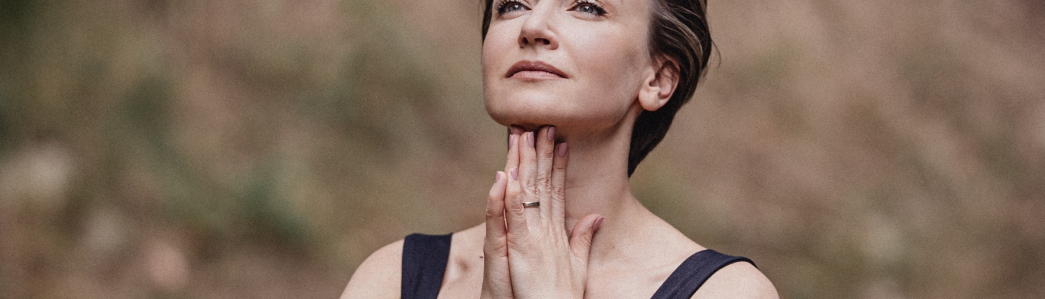 Maria Wade, executive coach and author, in a reflective pose outdoors with hands folded beneath her chin.