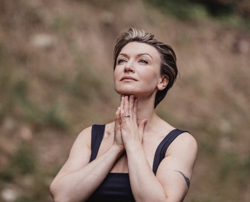 Maria Wade, executive coach and author, in a reflective pose outdoors with hands folded beneath her chin.