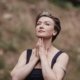 Maria Wade, executive coach and author, in a reflective pose outdoors with hands folded beneath her chin.